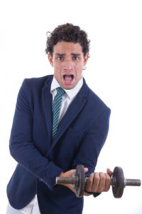 businessman struggling with a small dumbell