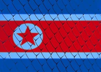 flag of North Korea behind chain link fence