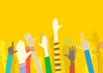racially diverse hands raised on yellow background
