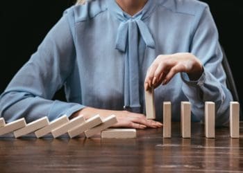 woman in blue picking up domino to stop domino effect