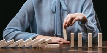 woman in blue picking up domino to stop domino effect