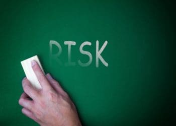 hand erasing "risk" on a chalkboard