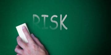hand erasing "risk" on a chalkboard