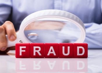 white magnifying glass hovering over fraud in red block letters