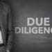 due diligence written on chalkboard next to businessman