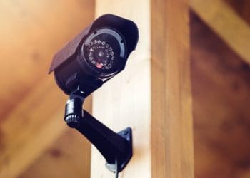black security camera attached to wood beam