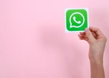 hand holding whatsapp icon on pink background