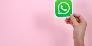 hand holding whatsapp icon on pink background