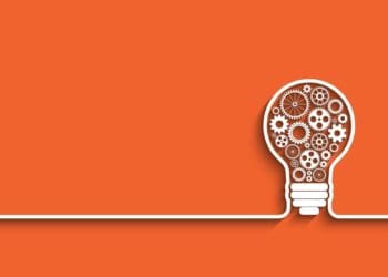 interlocking cogs in a light bulb on orange background