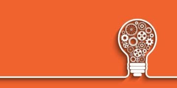 interlocking cogs in a light bulb on orange background