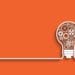 interlocking cogs in a light bulb on orange background