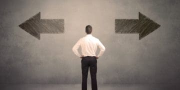 businessman facing opposite arrows on the wall