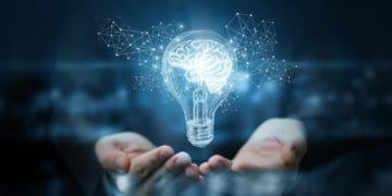 illuminated light bulb with brain inside, in businessman's hands