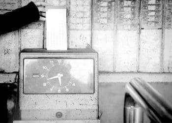black and white image of hand using punch clock