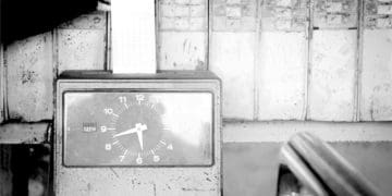 black and white image of hand using punch clock