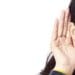 woman holding hand behind ear to hear better