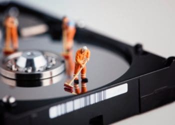 tiny maintenance workers in orange coveralls cleaning a hard drive