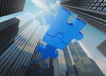 connected blue puzzle pieces joining skyscrapers