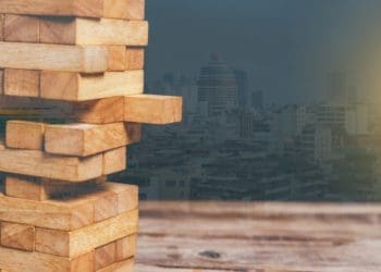 jenga tower with protruding block and cityscape in background