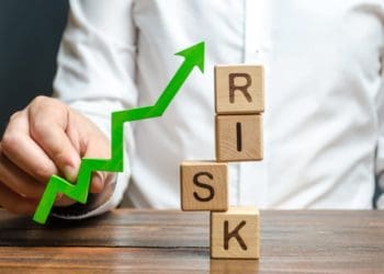 businessman holding a green up arrow near the word risk, improving business resilience, reducing risks