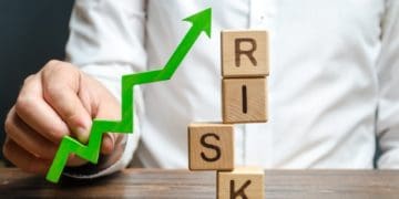 businessman holding a green up arrow near the word risk, improving business resilience, reducing risks