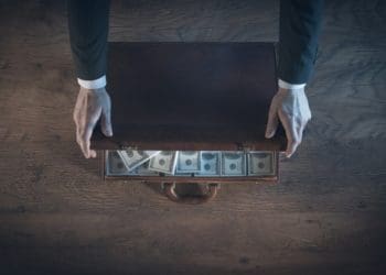 businessman closing briefcase full of cash