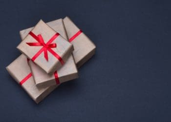 gift boxes in brown paper with red ribbon on black background