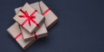 gift boxes in brown paper with red ribbon on black background