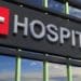 hospital sign on building with sky reflecting in windows
