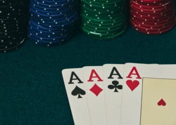 four aces on card table with stacks of poker chips