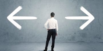 businessman facing wall with arrows pointing left and right