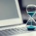 hourglass with blue sand on laptop