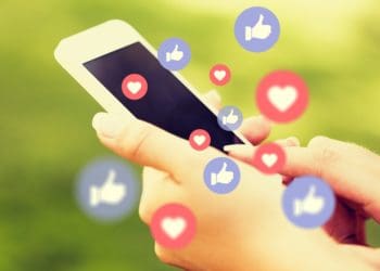 woman holding smartphone with many "like" and "heart" reactions