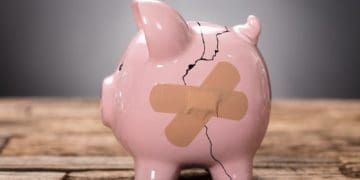closeup photo of broken piggy bank held together with two band aids