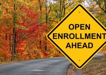 yellow "open enrollment ahead" sign posted on road in autumn