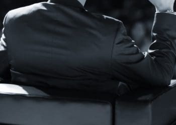 businessman sitting on stage addressing auditorium