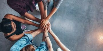 top view of team with hands stacked in half huddle