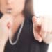 businesswoman in black blowing a whistle and pointing at the camera