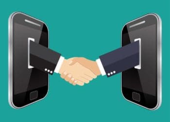 illustration of businessmen shaking hands through smartphone screens