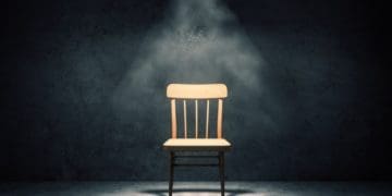 illuminated wooden chair in dark concrete room