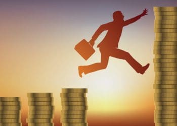 businessman jumping between increasingly taller stacks of coins