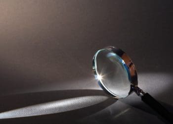 closeup of magnifying glass on gray background