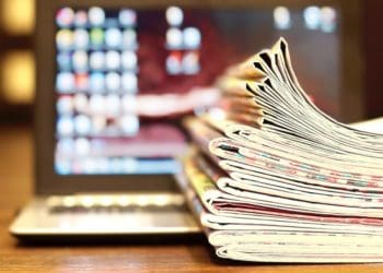 stack of newspapers on laptop