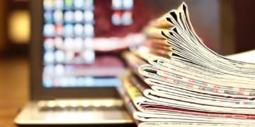 stack of newspapers on laptop