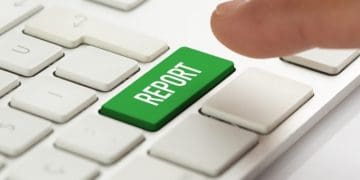 finger over green report button on white keyboard