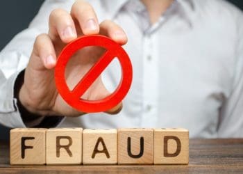 man holds prohibited symbol above wooden block letters spelling fraud