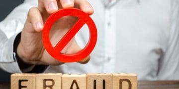 man holds prohibited symbol above wooden block letters spelling fraud