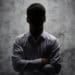 unidentifiable businessman with arms crossed, face in shadow
