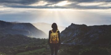 woman in yellow backpack looking out over landscape