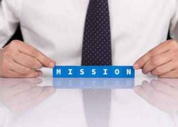 the word mission spelled in blue blocks on reflective surface